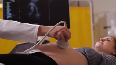 Hamile kadın ultrason taraması sırasında yatakta yatıyor.