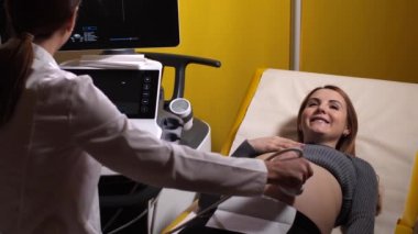 Ultrason taramasında gülümseyen hamile kadın.