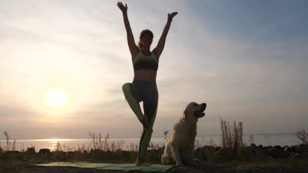 Adatta donna che pratica yoga sulla riva del mare al tramonto — Video Stock