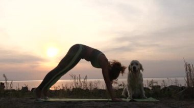 Gün batımında sahilde yoga yapan sağlıklı bir kadın.