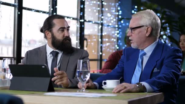 Зрелые бизнесмены обсуждают партнерство в кафе — стоковое видео