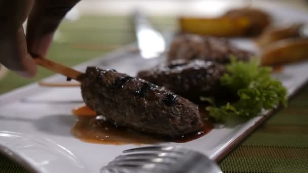 Närbild fingrar tar kött kebab från plattan — Stockvideo