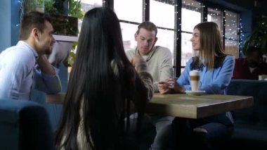 Positive friends communicating in cozy coffee shop