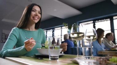 Restoranda yemek yiyen ve iletişim kuran Asyalı kadın.