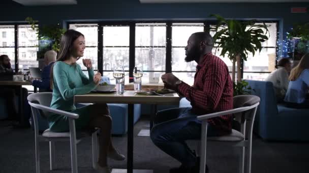 Vielfältiges Paar isst, kommuniziert im Restaurant — Stockvideo