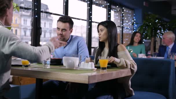 Группа друзей разговаривает, ест в ресторане — стоковое видео