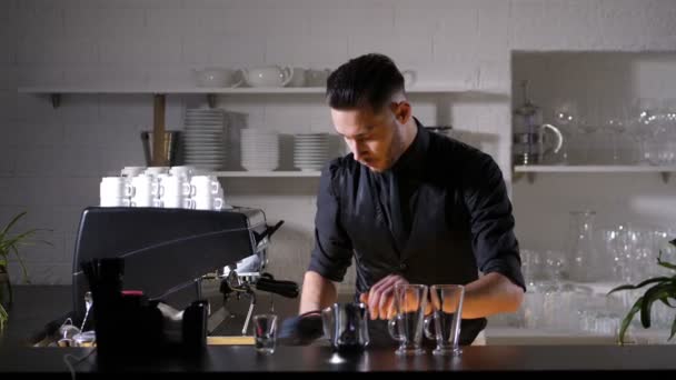 Jovem barista elegante derramando leite no jarro — Vídeo de Stock