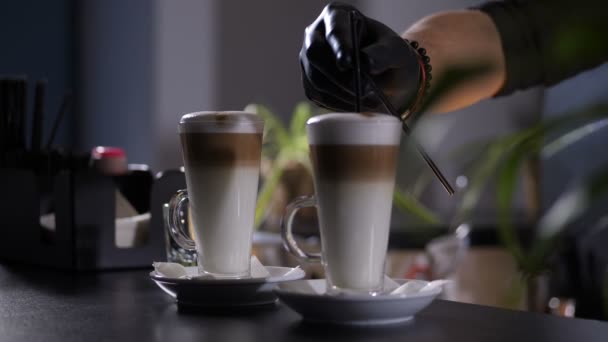 Hand des Baristas steckt Strohhalme in Latte-Gläser — Stockvideo