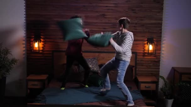 Радостные друзья смешанной расы во время боя подушками — стоковое видео