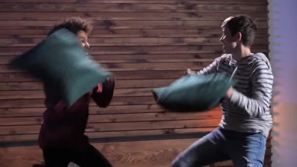 Счастливые друзья валяют дурака во время боя подушками — стоковое видео