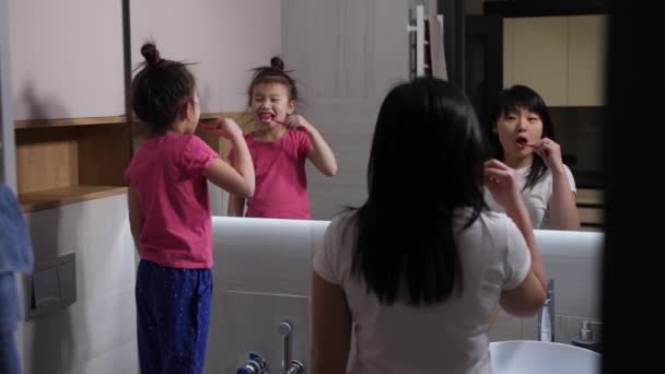 Evening toothbrushing of asian mom and daughter — Stock Video