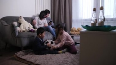 Çocuklar yalnız oynarken Asyalı aileler telefon kullanıyor.