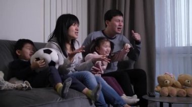Asyalı aile, yurt içinde futbol maçı izliyor.