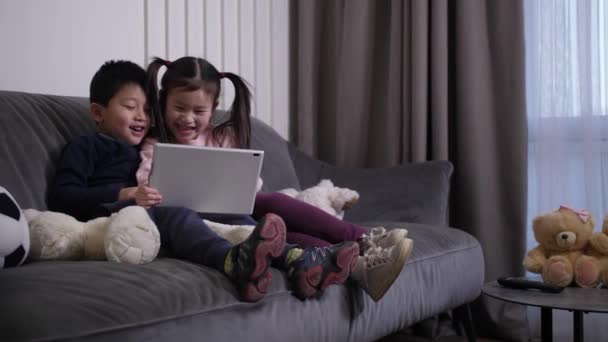 Riendo niños chinos viendo dibujos animados en la tableta — Vídeo de stock