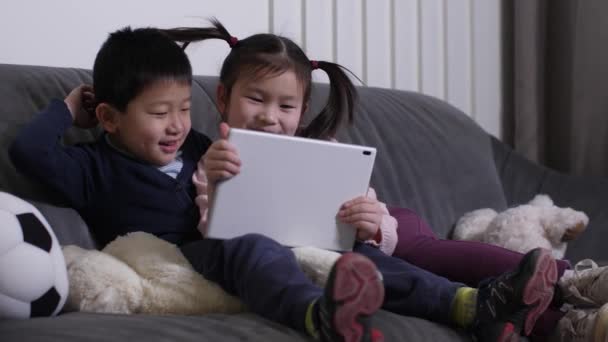 Lächelnde asiatische Kinder sehen lustige Videos auf dem Tablet — Stockvideo