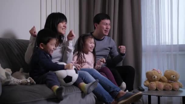 Excited asian family watching football match on TV — Stock Video