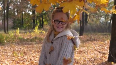 Neşeli genç kız dökülen yaprakları kusuyor.