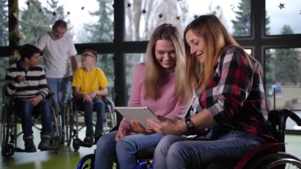 Γελώντας γυναίκες με αναπηρία σε αναπηρική καρέκλα χρησιμοποιώντας δισκίο — Αρχείο Βίντεο
