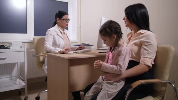 Doctor trabajando en PC y hablando con paciente chica — Vídeo de stock