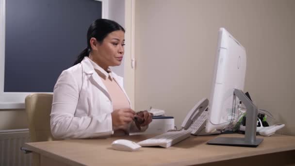 피곤 한 소아과 의사 가 병원에서 컴퓨터로 일하는 모습 — 비디오