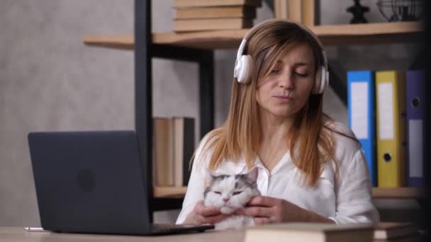 Жінка-працівник в навушниках розслабляється під час роботи — стокове відео