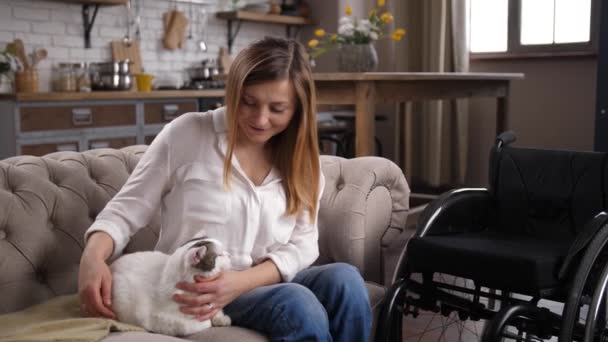 Joyful mulher deficiente acariciando gato sentado no sofá — Vídeo de Stock