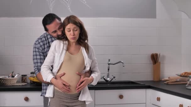 Radostný pár očekává dítě mazlení v kuchyni — Stock video