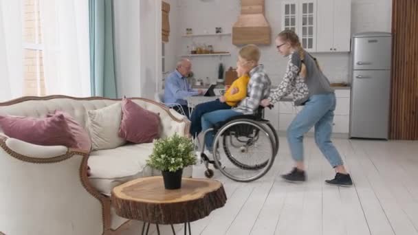 Chica montando silla de ruedas con la abuela y el hermano — Vídeos de Stock