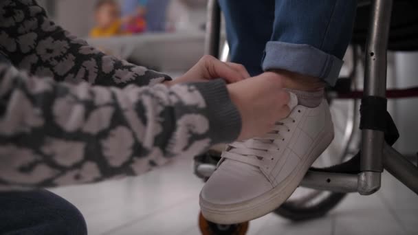 Руки девушки в шнурках для бабушки-инвалида — стоковое видео