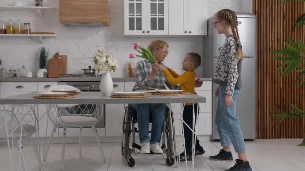 Amar a los niños dando flores a la abuela discapacitada — Vídeos de Stock