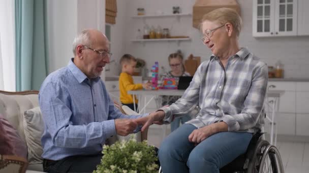 Caring old husband developing disabled wifes hand — Stock Video