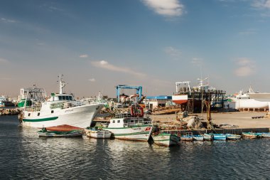 Balıkçı tekneleri bir liman ve mavi gökyüzü.