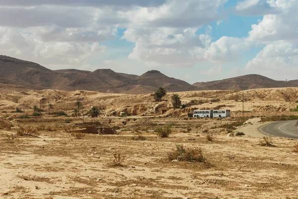 De bus gaat op de weg langs de rotsachtige Saharawoestijn, Tunesië. — Stockfoto