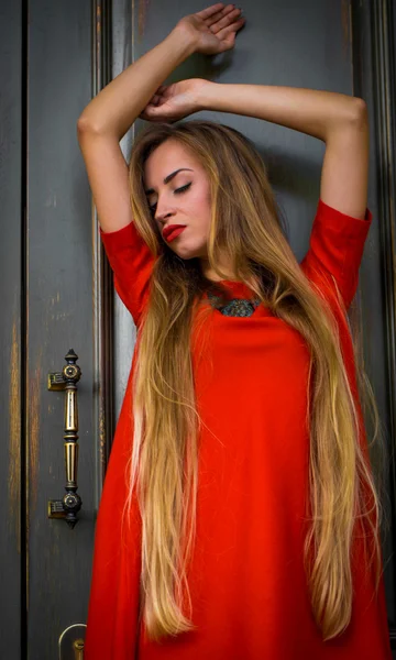 Fata tânără la modă pe un fundal de ușă de epocă în rochie roșie cu păr lung — Fotografie, imagine de stoc