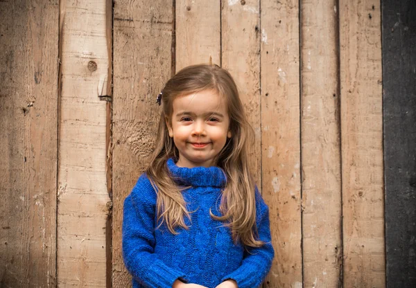 Маленькая девочка в стильной одежде и красивом деревянном фоне — стоковое фото