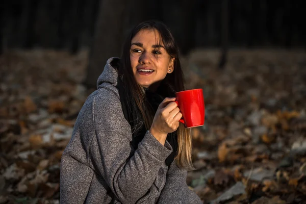 Schöne Mädchen im herbstlichen Wald mit einer heißen Tasse Tee — Stockfoto