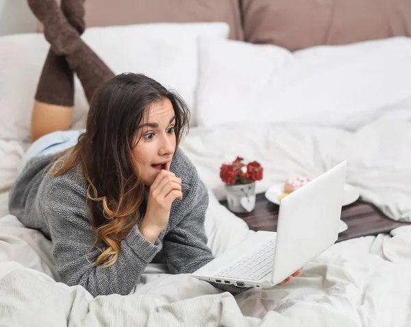 Kız yatakta bir fincan ve bilgisayar ile