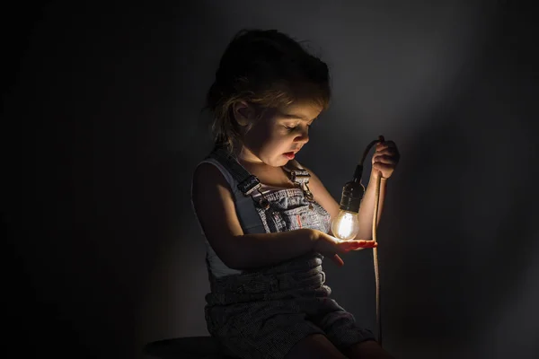 Маленькая милая девочка с лампочкой в руке — стоковое фото