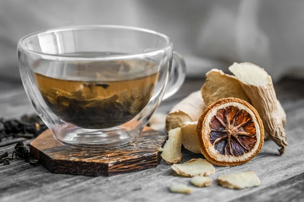 Νεκρή φύση με διαφανές φλιτζάνι τσάι σε φόντο ξύλινη — Φωτογραφία Αρχείου