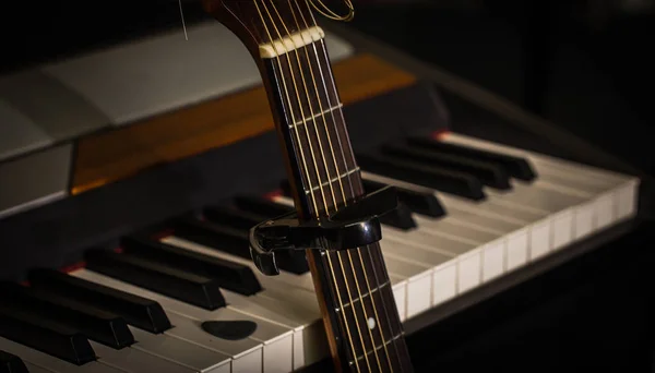 Musical instruments piano keys and acoustic guitar capadaster — Stock Photo, Image