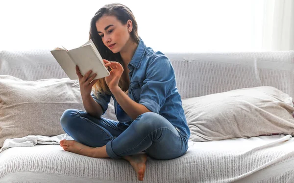 Blanco acogedora cama y una hermosa chica, leyendo un libro, conceptos de hogar y comodidad — Foto de Stock