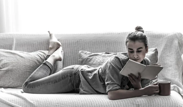 Białe łóżko przytulne i piękne dziewczyny, czytając książkę i picia gorących napojów, koncepcji domu i komfort — Zdjęcie stockowe