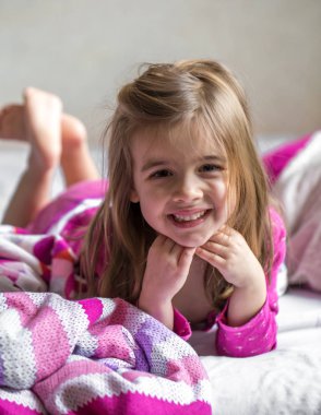 Küçük kız yatakta yatıyor.