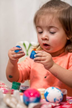 küçük kız boyalar Paskalya yumurtaları çizer