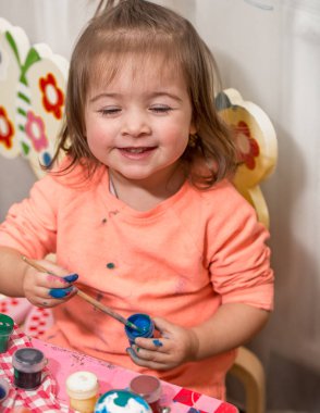 küçük kız boyalar Paskalya yumurtaları çizer