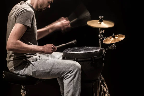 Hombre tocando un tambor djembe y platillos sobre un fondo negro — Foto de Stock