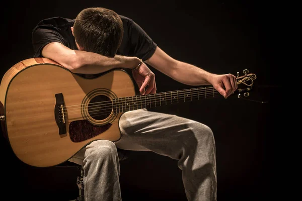 Jovem com guitarra acústica sobre fundo preto — Fotografia de Stock