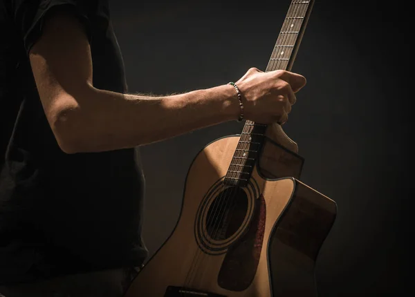 Jovem com guitarra acústica sobre fundo preto — Fotografia de Stock