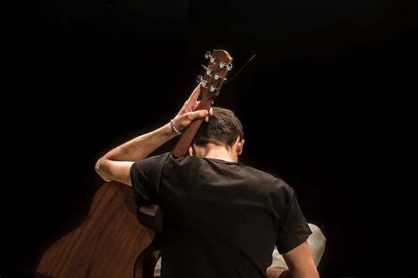 Jeune homme avec guitare acoustique sur fond noir — Photo