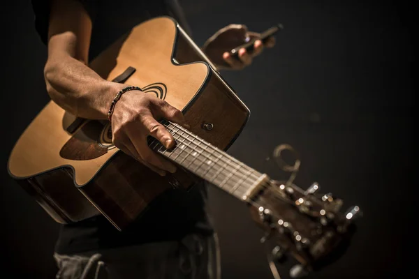 Jovem com guitarra acústica sobre fundo preto — Fotografia de Stock